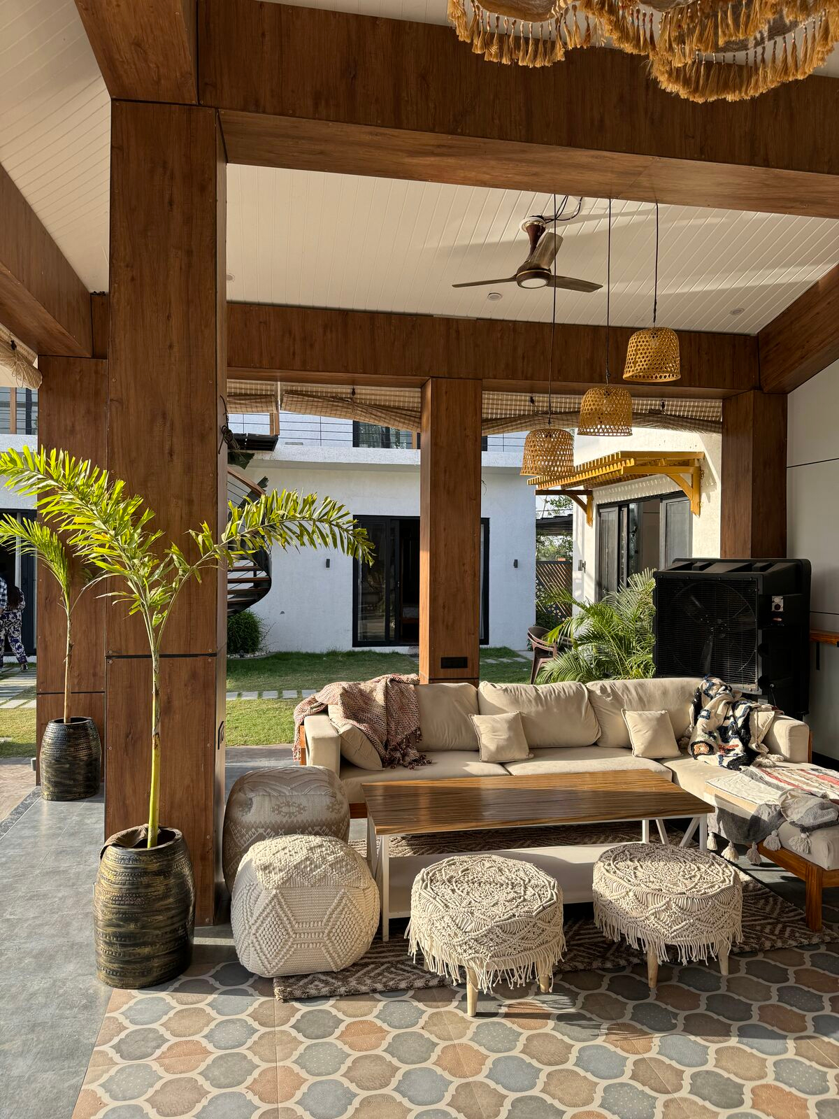 Open-air Bali-style lounge with carved wood pillars, rattan lights and macramé seating