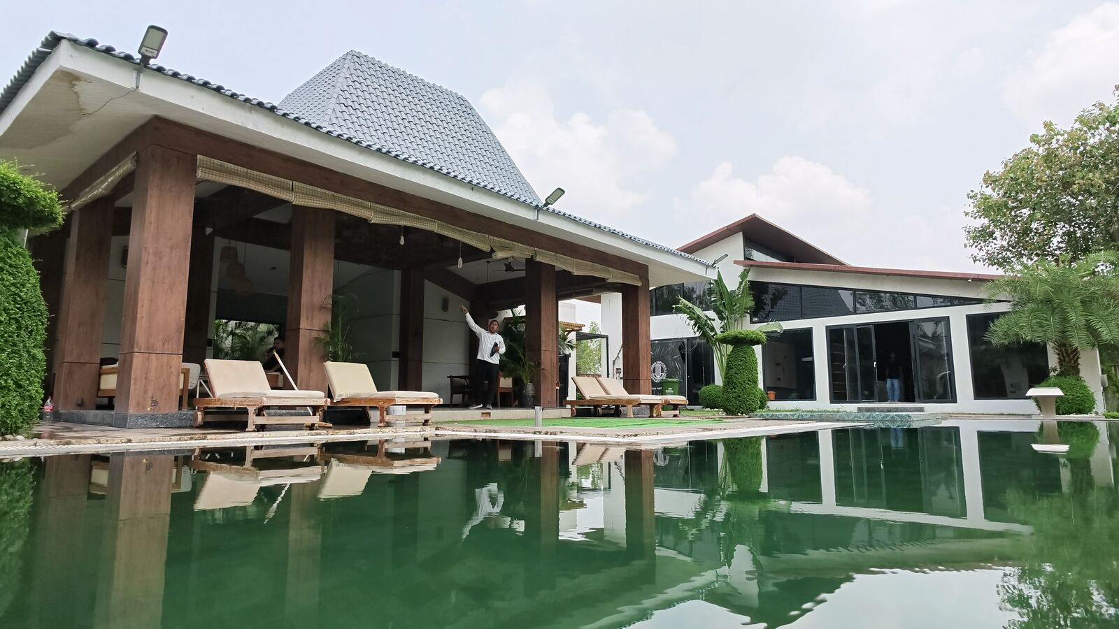 Poolside pavilion with sun loungers reflected in the water